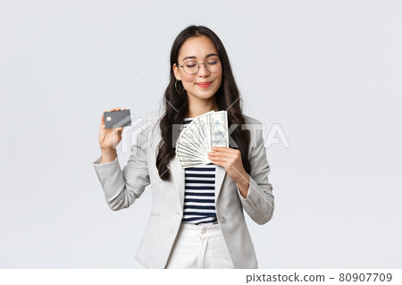 Business, finance and employment, entrepreneur and money concept. Successful pleased businesswoman earn cash, smiling with satisfaction, showing dollars and credit card 80907709
