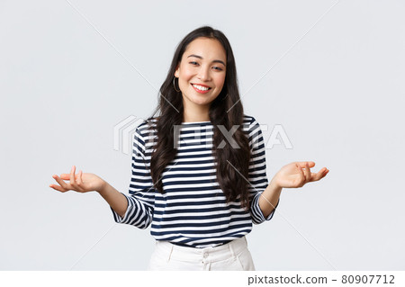 Lifestyle, beauty and fashion, people emotions concept. Smiling cute clueless girl dont have idea, no answer, shrugging with hands spread sideways, standing white background 80907712