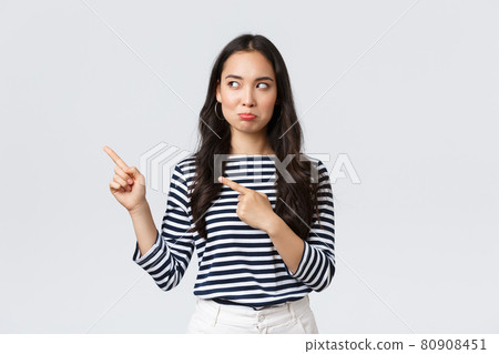 Lifestyle, beauty and fashion, people emotions concept. Disappointed sad asian girl complaining, feeling regret or jealousy as pouting uneasy and pointing fingers left at promo banner 80908451