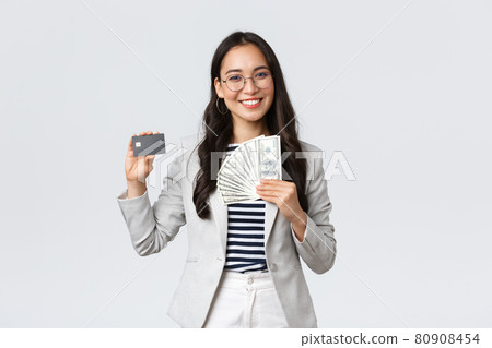 Business, finance and employment, entrepreneur and money concept. Successful asian businesswoman showing how increase income, hold credit card and money, smiling camera Business, finance and employment, entrepreneur and money concept. Successful asian businesswoman showing how increase income, hold credit card and money, smiling camera 80908454