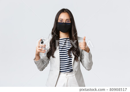 Business, finance and employment, covid-19 preventing virus and social distancing concept. Smiling businesswoman in face mask showing hand sanitizer and thumbs-up, ask to use it Business, finance and employment, covid-19 preventing virus and social distancing concept. Smiling businesswoman in face mask showing hand sanitizer and thumbs-up, ask to use it 80908517