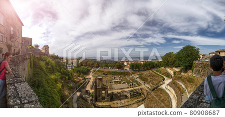 Volterra, Tuscany, Italy. Amazing large format panoramic photo of the imposing Roman amphitheater. A middle-aged woman and some boys are watching her. Volterra, Tuscany, Italy. Amazing large format panoramic photo of the imposing Roman amphitheater. A middle-aged woman and some boys are watching her. 80908687