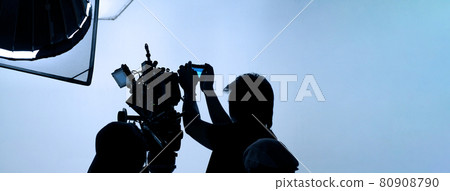 Video production behind the scenes. Making of TV commercial movie that film crew team lightman and cameraman working together with film director in studio. film production concept. Silhouette style. 80908790