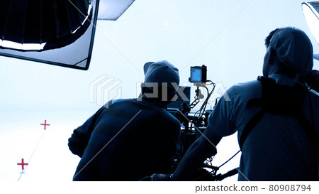 Video production behind the scenes. Making of TV commercial movie that film crew team lightman and cameraman working together with film director in studio. film production concept. Silhouette style. 80908794