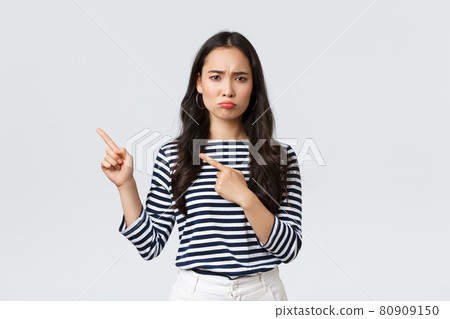 Lifestyle, beauty and fashion, people emotions concept. Disappointed sad asian girl complaining, feeling regret or jealousy as pouting uneasy and pointing fingers left at promo banner Lifestyle, beauty and fashion, people emotions concept. Disappointed sad asian girl complaining, feeling regret or jealousy as pouting uneasy and pointing fingers left at promo banner 80909150