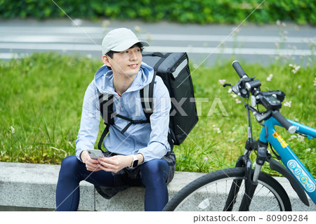 A man riding a bicycle and delivering in the city A man riding a bicycle and delivering in the city 80909284