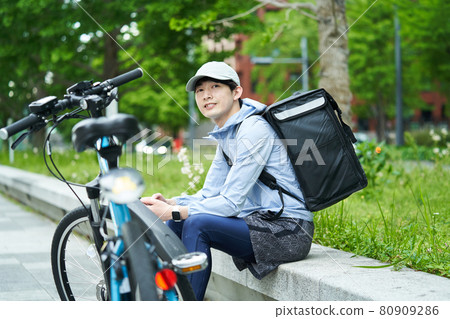 A man riding a bicycle and delivering in the city 80909286