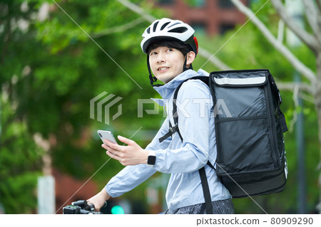 A man riding a bicycle and delivering in the city 80909290