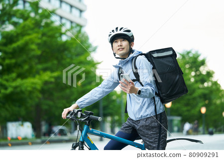 A man riding a bicycle and delivering in the city 80909291