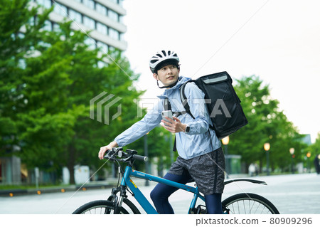 A man riding a bicycle and delivering in the city A man riding a bicycle and delivering in the city 80909296