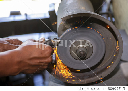The machine operator grinding the drill tool with abrasive wheel. 80909745