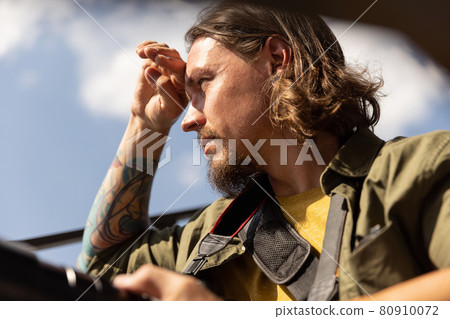 Portrait of young man, photographer, cameraman with professional camera, equipment during working summer day outdoors. Concept of occupation, job, education Portrait of young man, photographer, cameraman with professional camera, equipment during working summer day outdoors. Concept of occupation, job, education 80910072