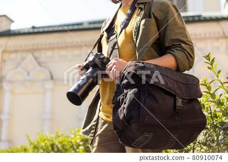 Portrait of young man, photographer, cameraman with professional camera, equipment during working summer day outdoors. Concept of occupation, job, education Portrait of young man, photographer, cameraman with professional camera, equipment during working summer day outdoors. Concept of occupation, job, education 80910074