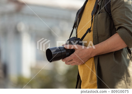 Cropped image of man, photographer, cameraman with professional camera, equipment during working summer day outdoors. Concept of occupation, job, education Cropped image of man, photographer, cameraman with professional camera, equipment during working summer day outdoors. Concept of occupation, job, education 80910075