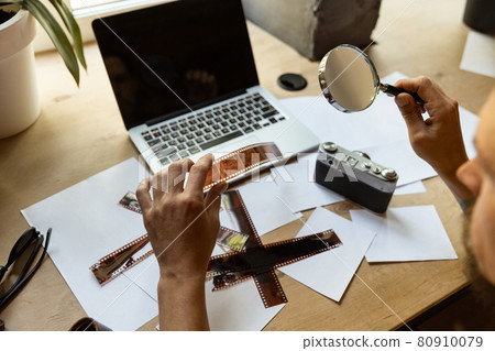Close-up hands and objects for photographer work. Laptop, loupe and photo films. Concept of occupation, job, education Close-up hands and objects for photographer work. Laptop, loupe and photo films. Concept of occupation, job, education 80910079