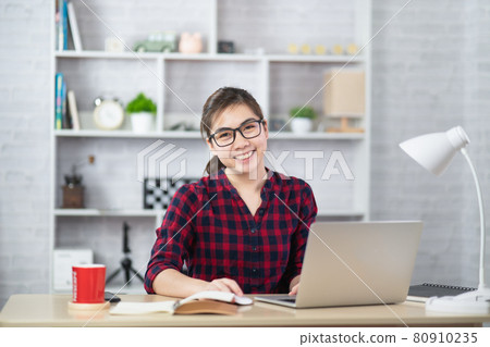 Beautiful asian woman relaxing using laptop computer while sitting on table. Creative girl working and typing on keyboard at home.work at home concept Beautiful asian woman relaxing using laptop computer while sitting on table. Creative girl working and typing on keyboard at home.work at home concept 80910235