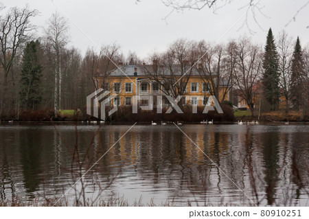 KOUVOLA, FINLAND - NOVEMBER 8, 2018: Wooden Rabbelugn Manor - Takamaan Kartano in dark autumn day. Swans are swimming in water. Wrede family house was built in 1820 on the river Kymijoki bank KOUVOLA, FINLAND - NOVEMBER 8, 2018: Wooden Rabbelugn Manor - Takamaan Kartano in dark autumn day. Swans are swimming in water. Wrede family house was built in 1820 on the river Kymijoki bank 80910251