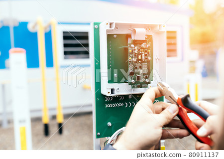 Adjustment of control and measuring equipment. The hands of an electrician or engineer with pliers 80911137
