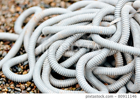 Plastic corrugated hose for insulation of wires lies on the crushed stone. 80911146