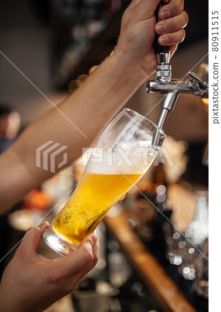 Hands pouring draught beer into a glass Hands pouring draught beer into a glass 80911515