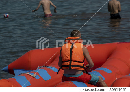 A man in a life jacket on a towed water tubing. A man in a life jacket on a towed water tubing. 80911661