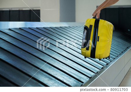 A woman takes a suitcase from the baggage carousel. A woman takes a suitcase from the baggage carousel. 80911703