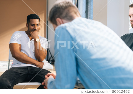Close-up back view of depressed young man sharing mental problem sitting in circle to other patients during group therapy session. 80912462