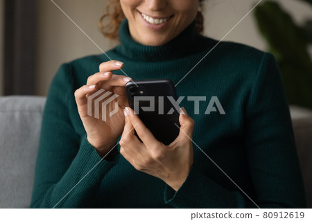 Close up smiling woman holding smartphone, typing on screen 80912619