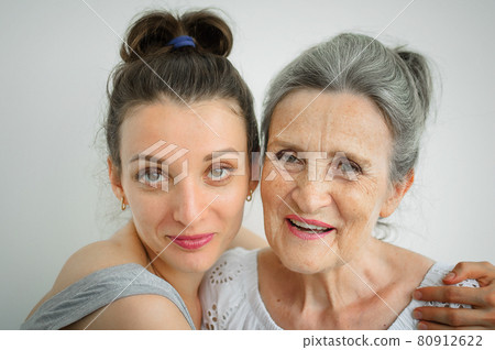 Happy senior mother is hugging her adult daughter, the women are laughing together, sincere family of different age generations having fun on white background, mothers day. Happy senior mother is hugging her adult daughter, the women are laughing together, sincere family of different age generations having fun on white background, mothers day. 80912622