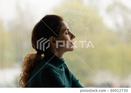 Profile view close up satisfied woman dreaming near rainy window 80912730