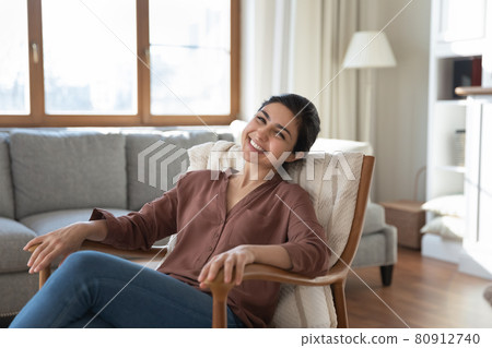 Portrait of happy Indian woman relax in cozy armchair 80912740