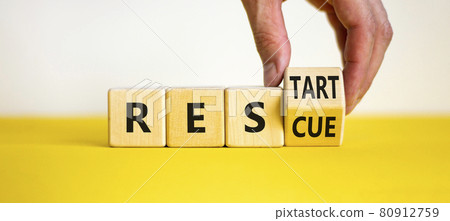 Rescue and restart symbol. Businessman hand turns cubes and changes the word 'rescue' to 'restart'. Beautiful yellow table, white background. Business and rescue - restart concept. Copy space. 80912759