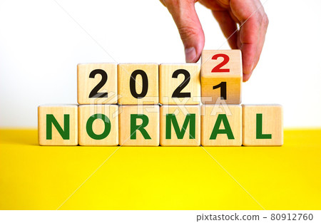 Symbol of covid-19 normal in 2022. Doctor turns a wooden cube and changes words 'normal 2021' to 'normal 2022'. Beautiful white background, copy space. Medical, covid-19 normal in 2022 concept. 80912760