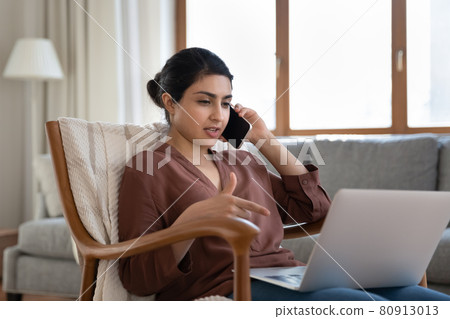 Indian woman work on laptop talk on smartphone Indian woman work on laptop talk on smartphone 80913013