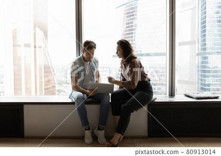 Mentor training intern, explaining data on laptop 80913014
