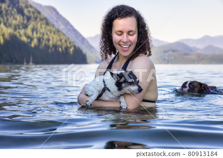 Caucasian Woman swimming in a lake with dog 80913184