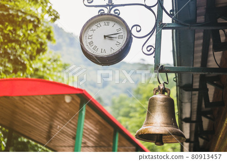 A large clock hangs at the train station in the forest. A large clock hangs at the train station in the forest. 80913457