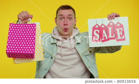 Happy student man showing Sale inscription banner text, advertising discounts low holidays prices 80913658