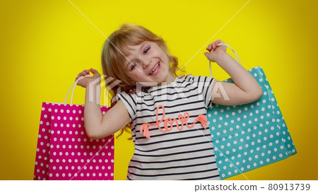 Kid girl showing shopping bags, advertising discounts, low prices, shopping on Black Friday holidays 80913739