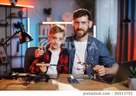 Happy father with son soldering modern laptop together 80913791