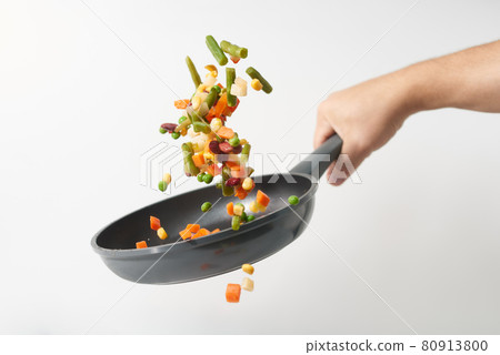 Fresh vegetables fly in a pan on a white background. Cooking with various chopped vegetables in a pan. The concept of healthy eating and diet.  80913800