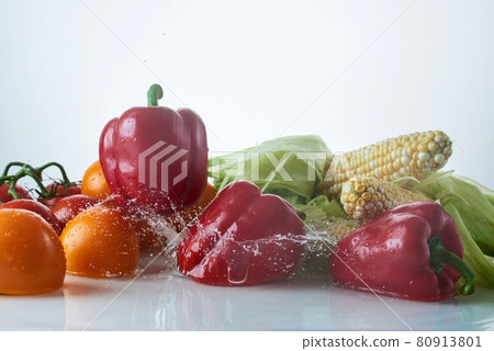 Fresh vegetables in water splashes on a white background, tomatoes, bell peppers, corn on the cob.  80913801