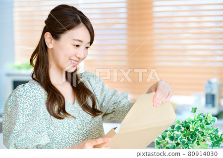 Young housewife opening mail luggage in the kitchen 80914030