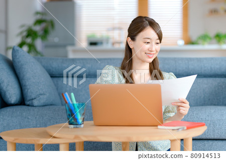 A young business woman teleworking in her living room 80914513