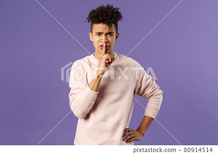 Portrait of disappointed, annoyed young bossy man trying work remote from home shushing at family talking too loud during his online video conference, hush with angry grimace 80914514