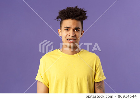 Waist-up portrait of young concerned hispanic man with worried gaze looking at camera, frowning being scared for friend stuck in troublesome situation, want help, stand purple background 80914544