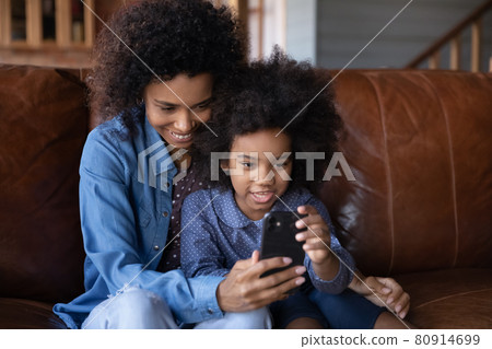 Happy biracial mom and daughter talk on cellphone call Happy biracial mom and daughter talk on cellphone call 80914699