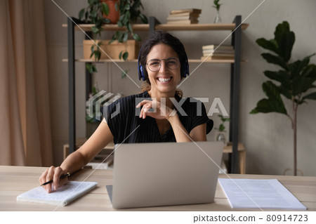 Head shot portrait of smiling woman in headphones using laptop Head shot portrait of smiling woman in headphones using laptop 80914723