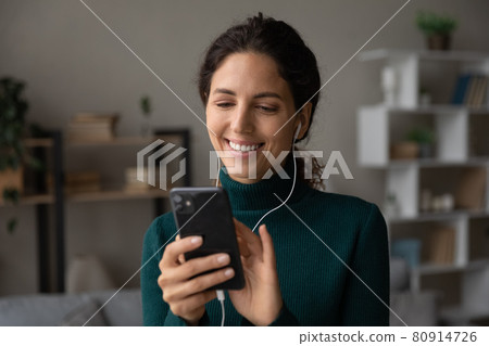 Head shot close up smiling woman in earphones using smartphone Head shot close up smiling woman in earphones using smartphone 80914726