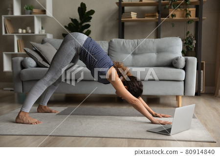 Side view woman practicing yoga online, doing Downward facing dog exercise Side view woman practicing yoga online, doing Downward facing dog exercise 80914840